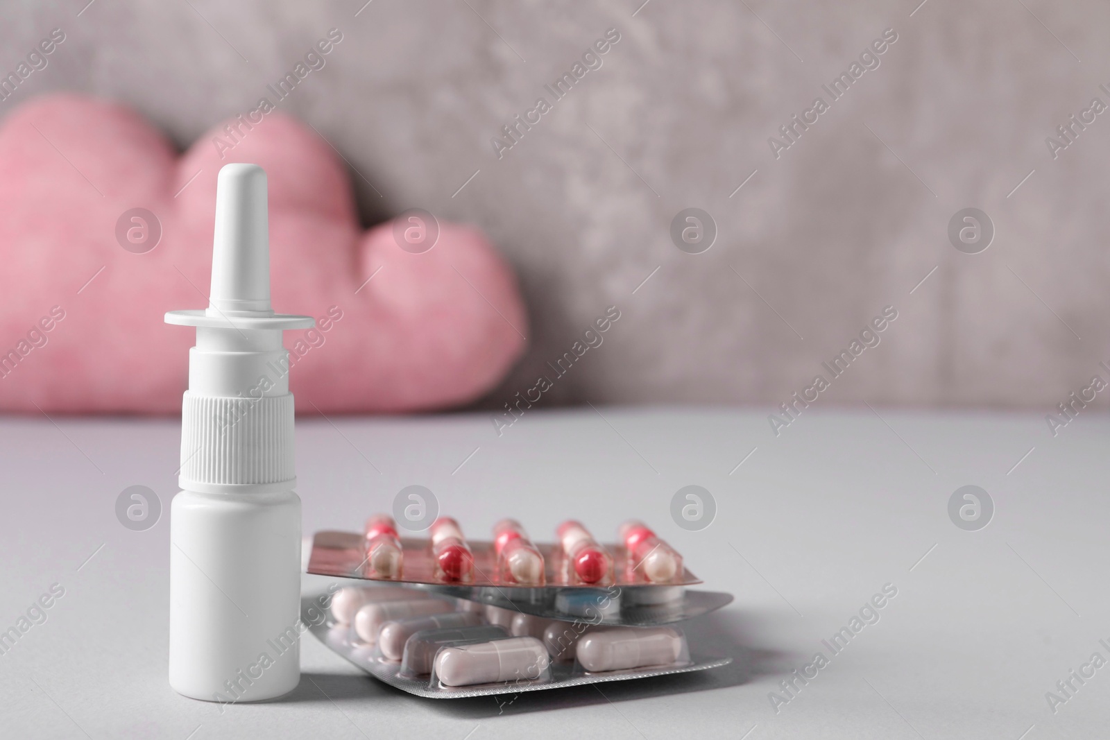 Photo of Pills and nasal spray on grey table, closeup. Space for text