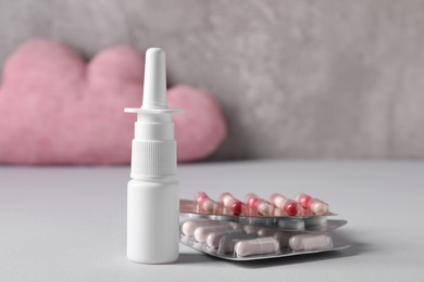 Pills and nasal spray on grey table, closeup