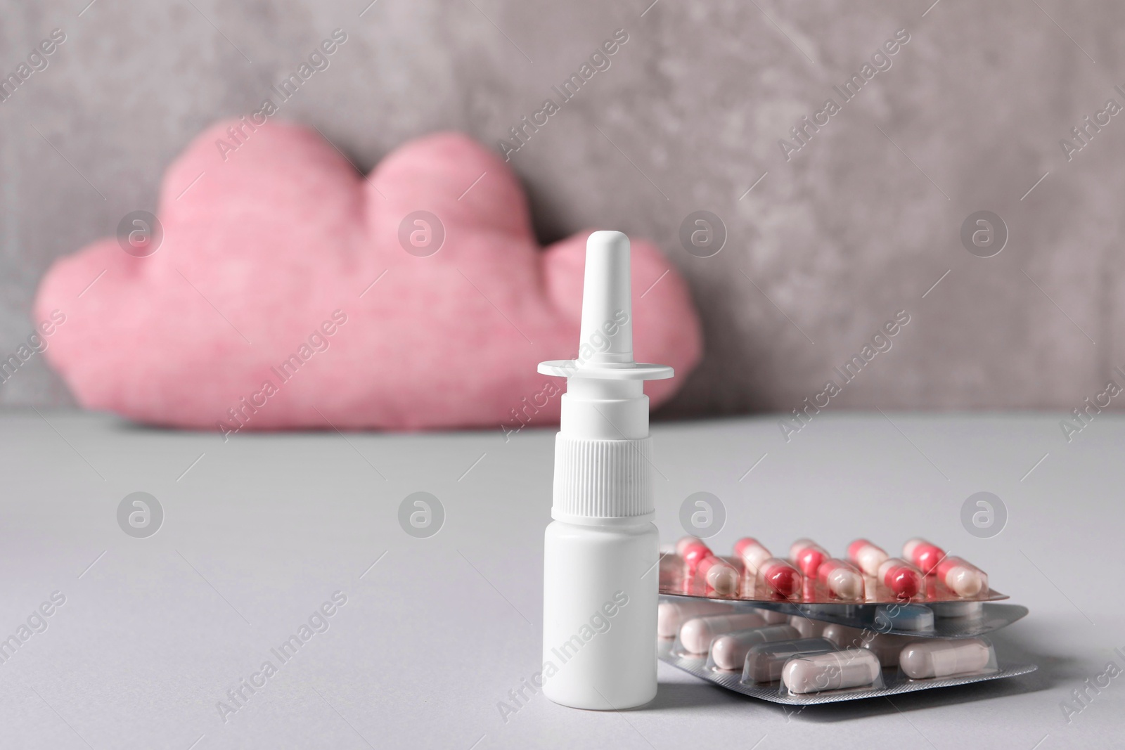 Photo of Pills and nasal spray on grey table, closeup. Space for text