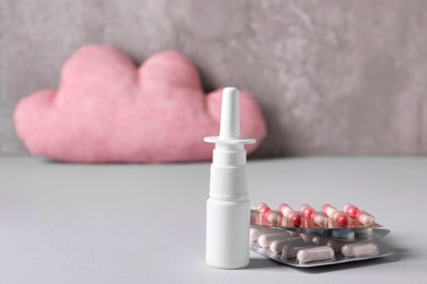 Photo of Pills and nasal spray on grey table, closeup. Space for text