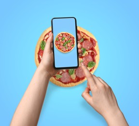 Image of Online food ordering. Woman holding smartphone with pizza on screen against light blue background, closeup