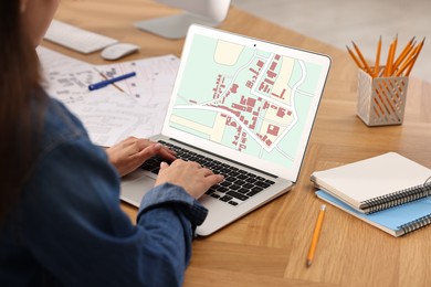 Image of Woman working with cadastral map on laptop at table in office, closeup