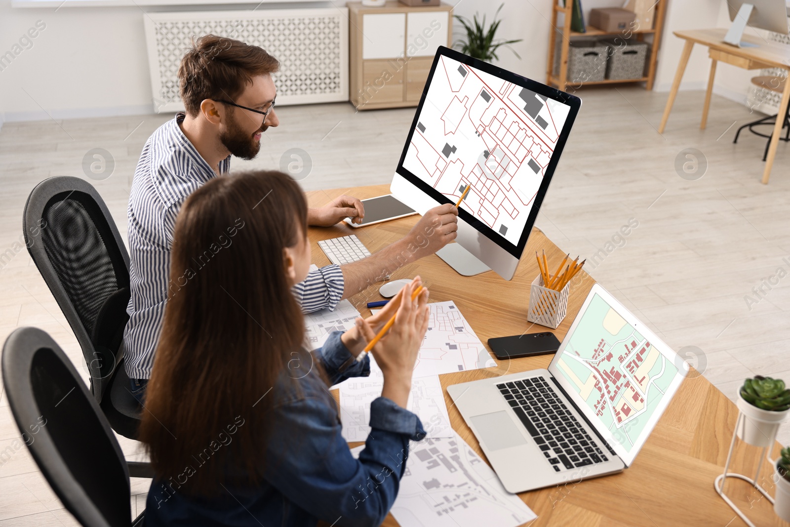 Image of Cartographers working with cadastral maps at table in office