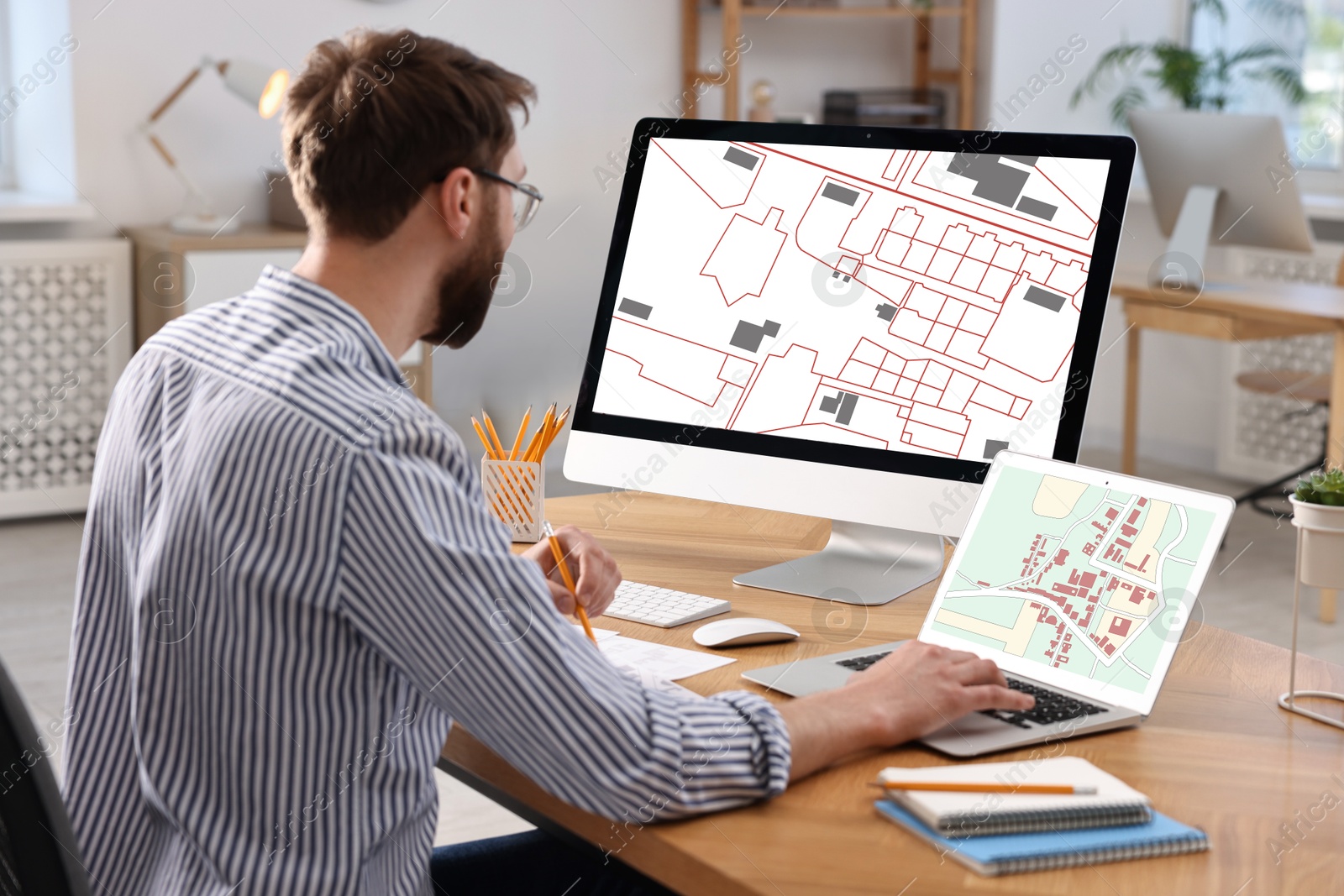 Image of Man working with cadastral map on computers at table in office