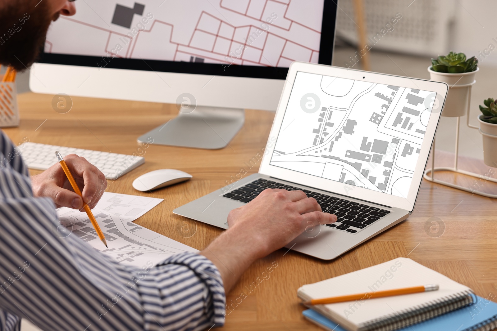 Image of Man working with cadastral map on laptop at table in office, closeup