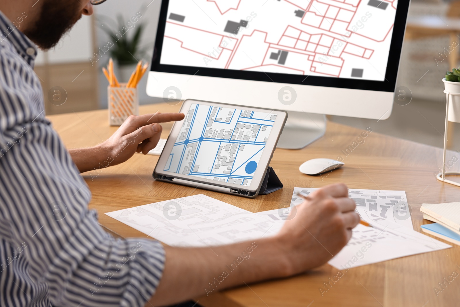 Image of Man working with cadastral map on tablet and computer at table in office, closeup