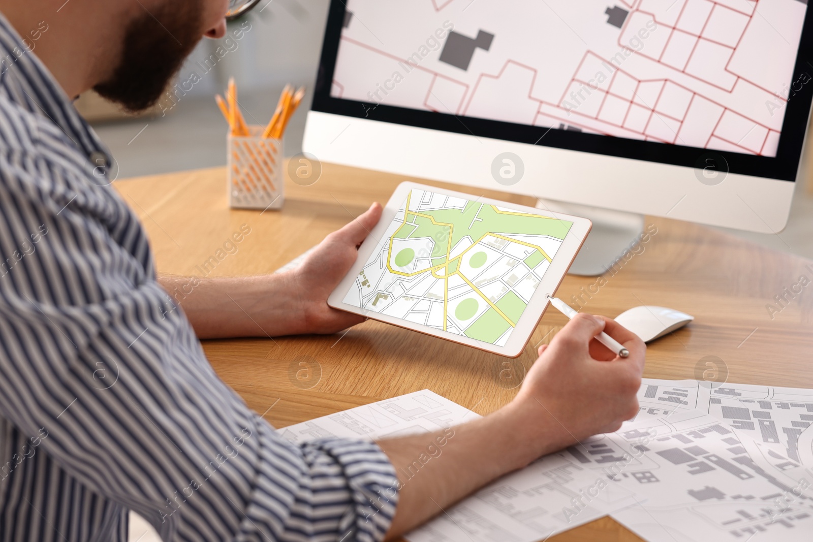 Image of Man working with cadastral map on tablet and computer at table in office, closeup