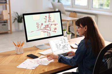 Woman working with cadastral map on computers at table in office