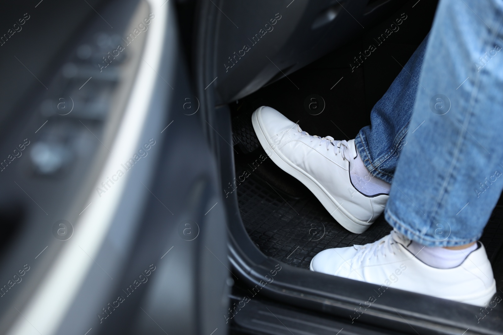 Photo of Man in sneakers pushing on pedal of car brake, closeup