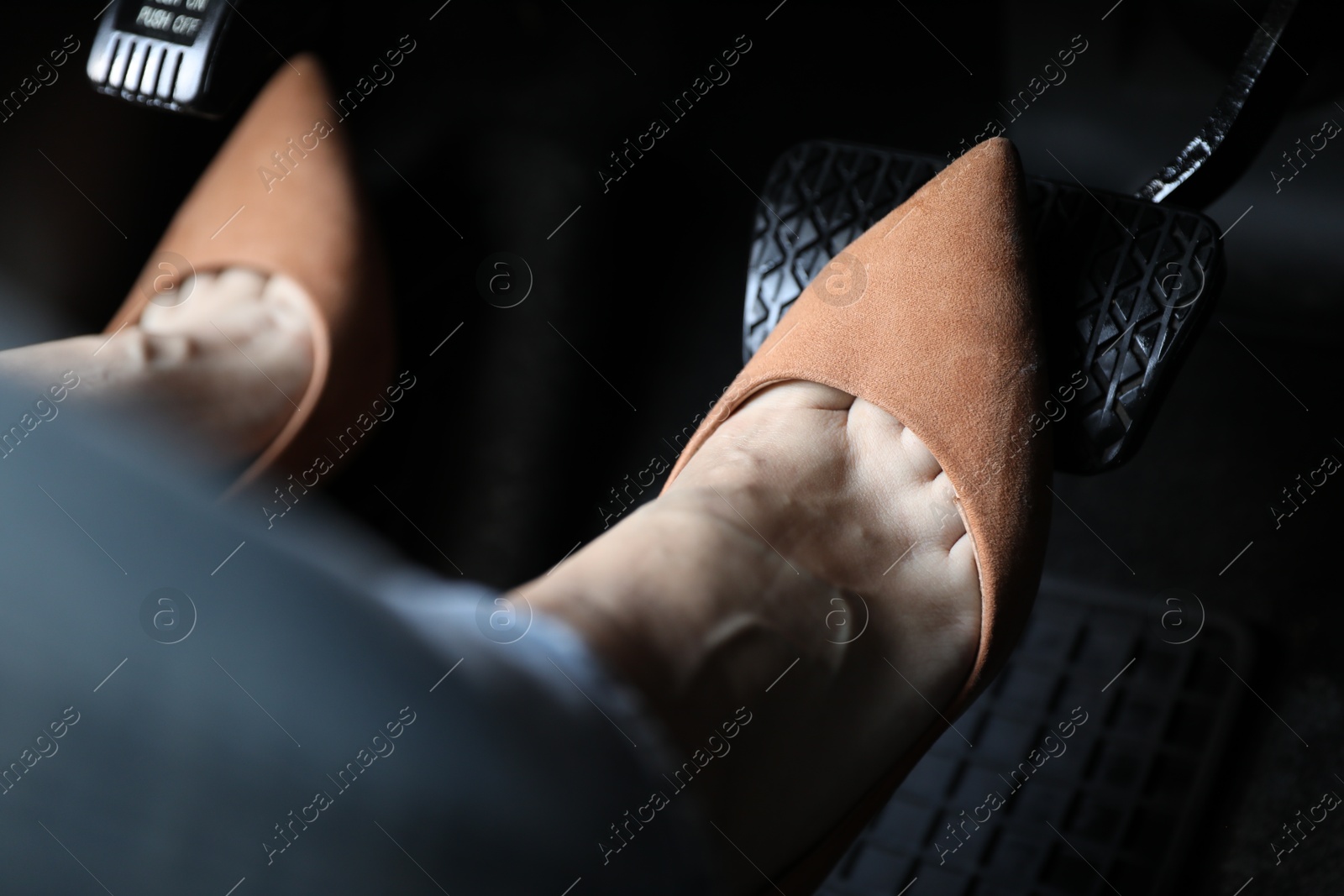 Photo of Woman in high heels pushing on pedal of car brake, closeup