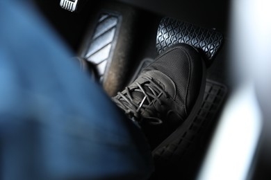 Man pushing on pedal of car brake, closeup