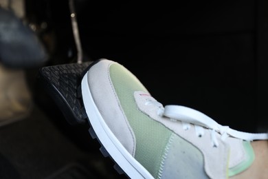 Woman pushing on pedal of car brake, closeup