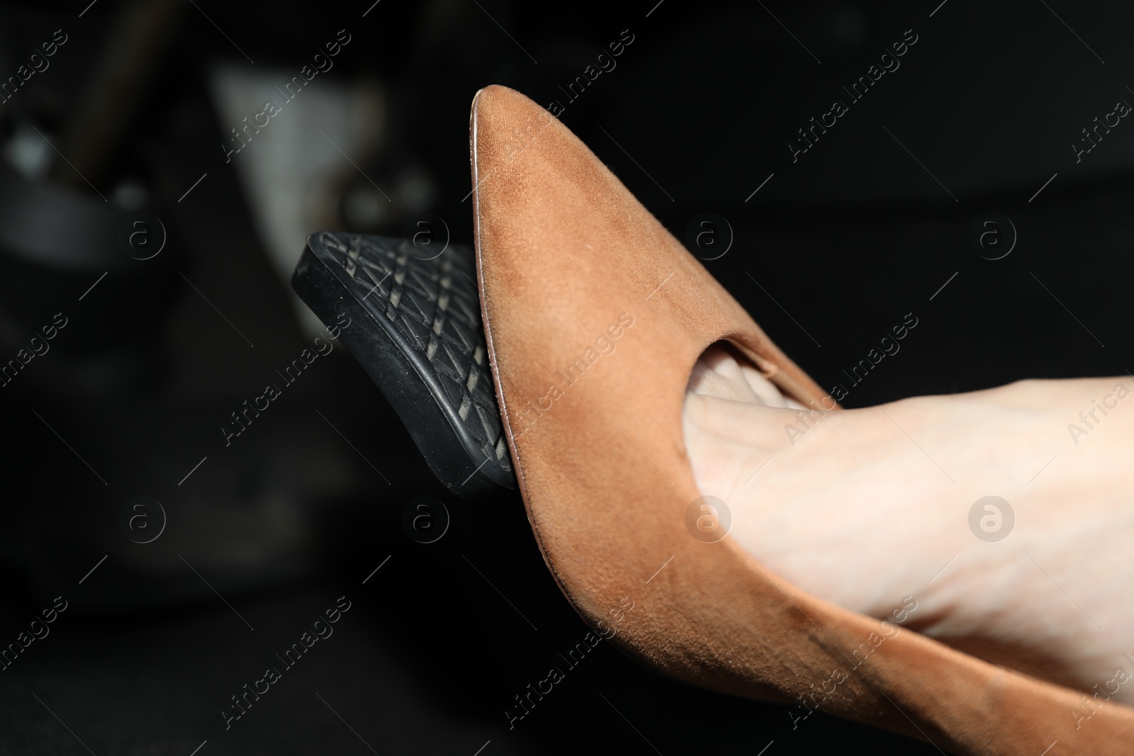 Photo of Woman in high heels pushing on pedal of car brake, closeup