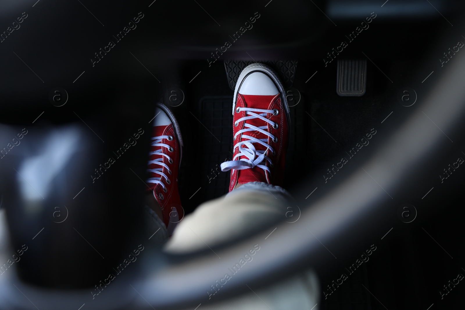 Photo of Woman in sneakers pushing on pedal of car brake, closeup