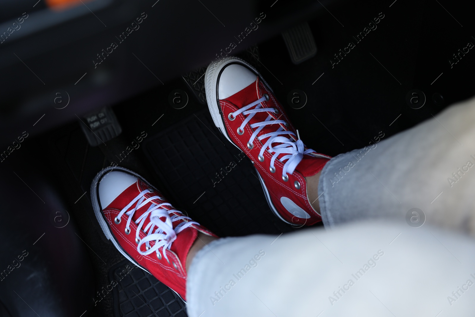 Photo of Woman in sneakers pushing on pedal of car brake, closeup