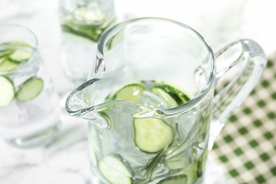 Refreshing cucumber water with rosemary in jug on table, closeup