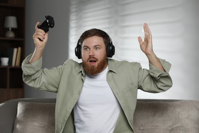 Photo of Surprised man in headphones with game controller at home