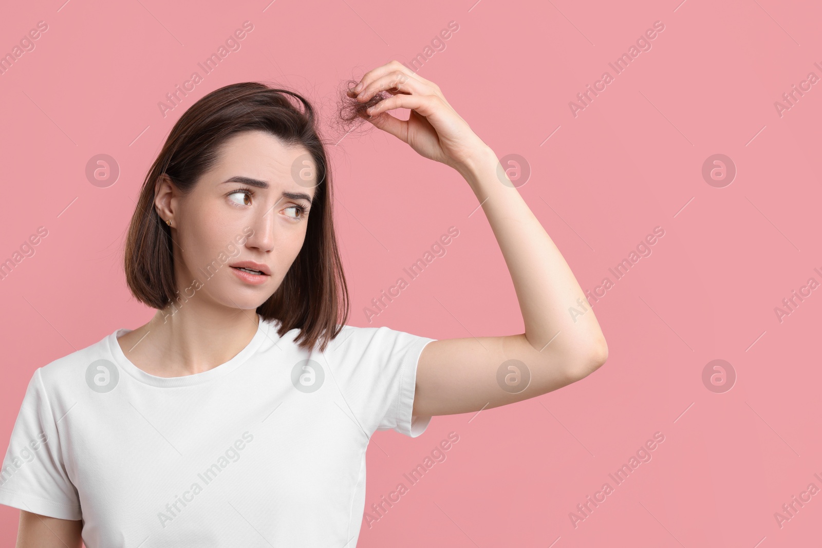 Photo of Young woman suffering from hair loss problem on pink background. Space for text