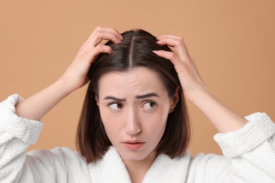 Sad woman with hair loss problem on light brown background