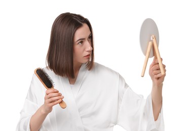 Young woman with hair loss problem looking at mirror on white background