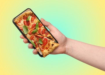 Online food ordering. Woman holding smartphone with pizza on screen against color gradient background, closeup. One slice sticking out of device