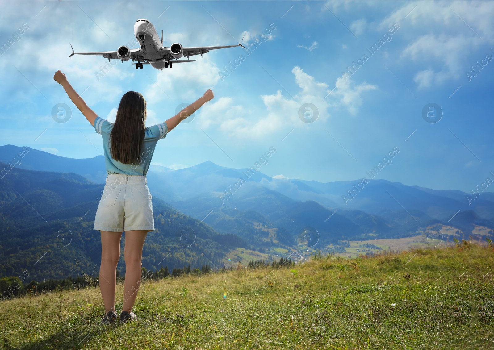 Image of Woman looking at airplane flying in sky over mountains, back view