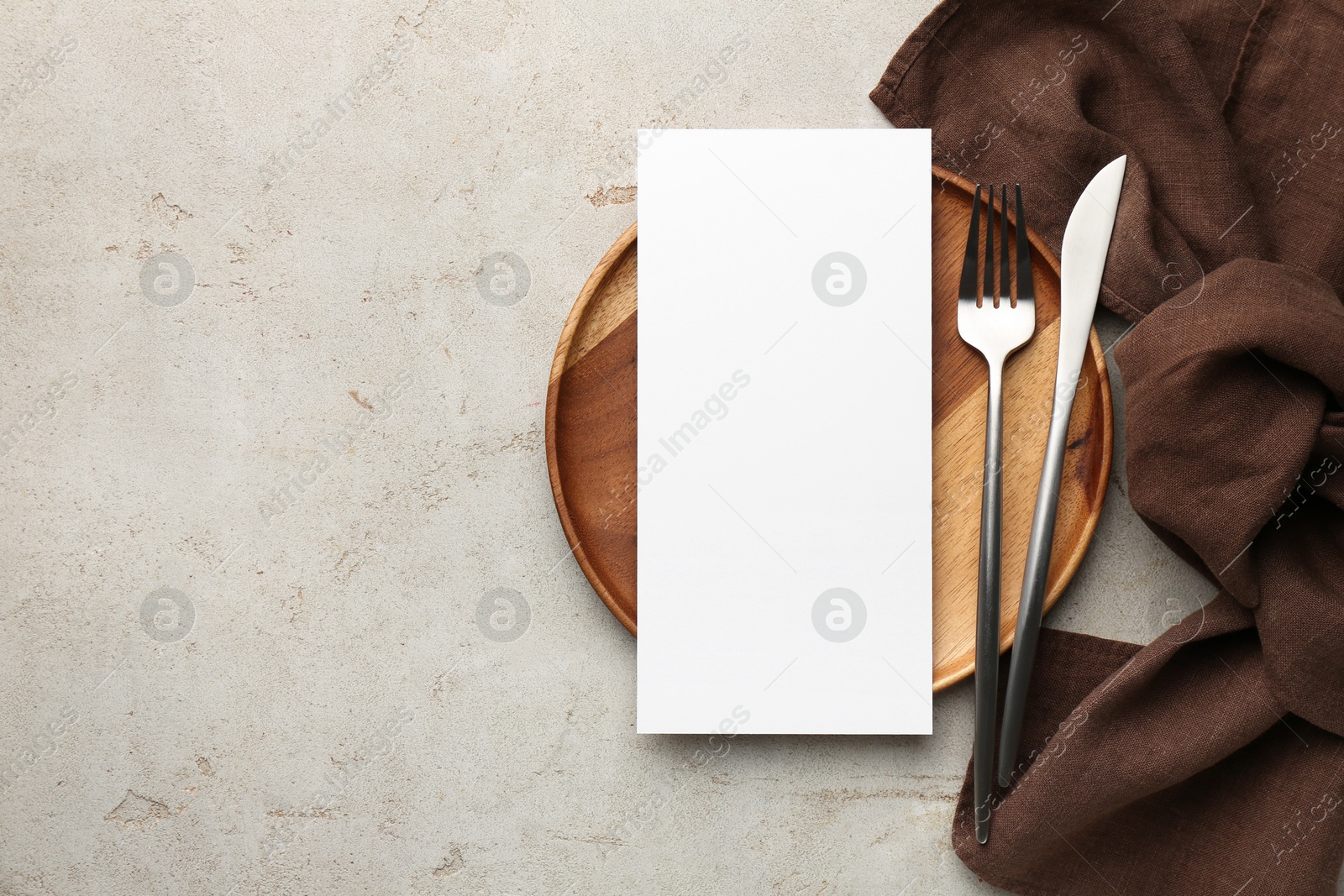 Photo of Empty menu, plate, cutlery and napkin on light grey table, top view. Mockup for design