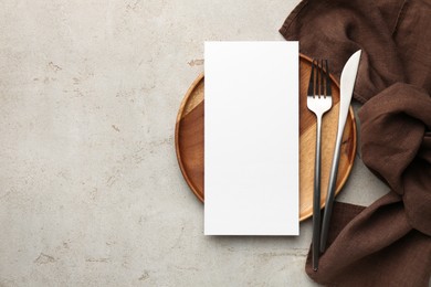 Photo of Empty menu, plate, cutlery and napkin on light grey table, top view. Mockup for design