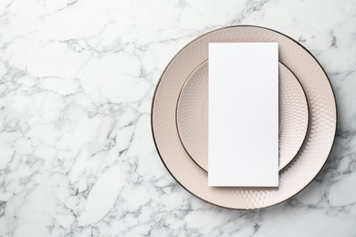 Photo of Empty menu and plates on white marble table, top view. Mockup for design