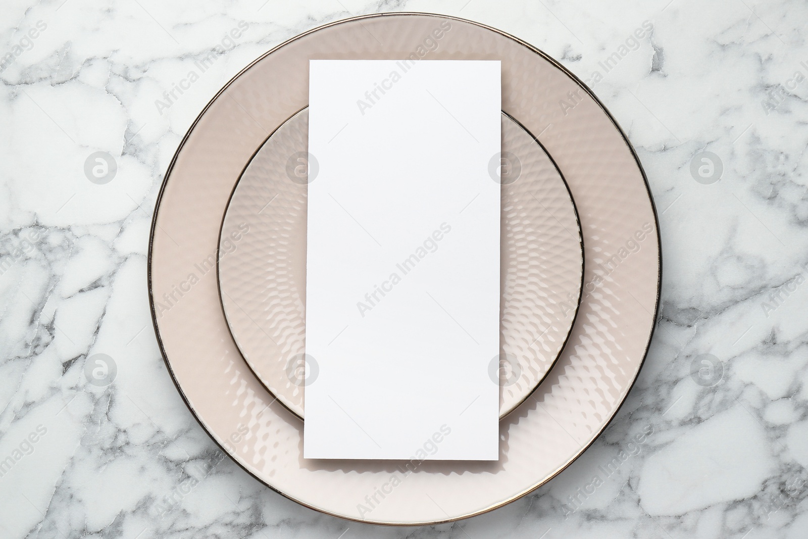 Photo of Empty menu and plates on white marble table, top view. Mockup for design