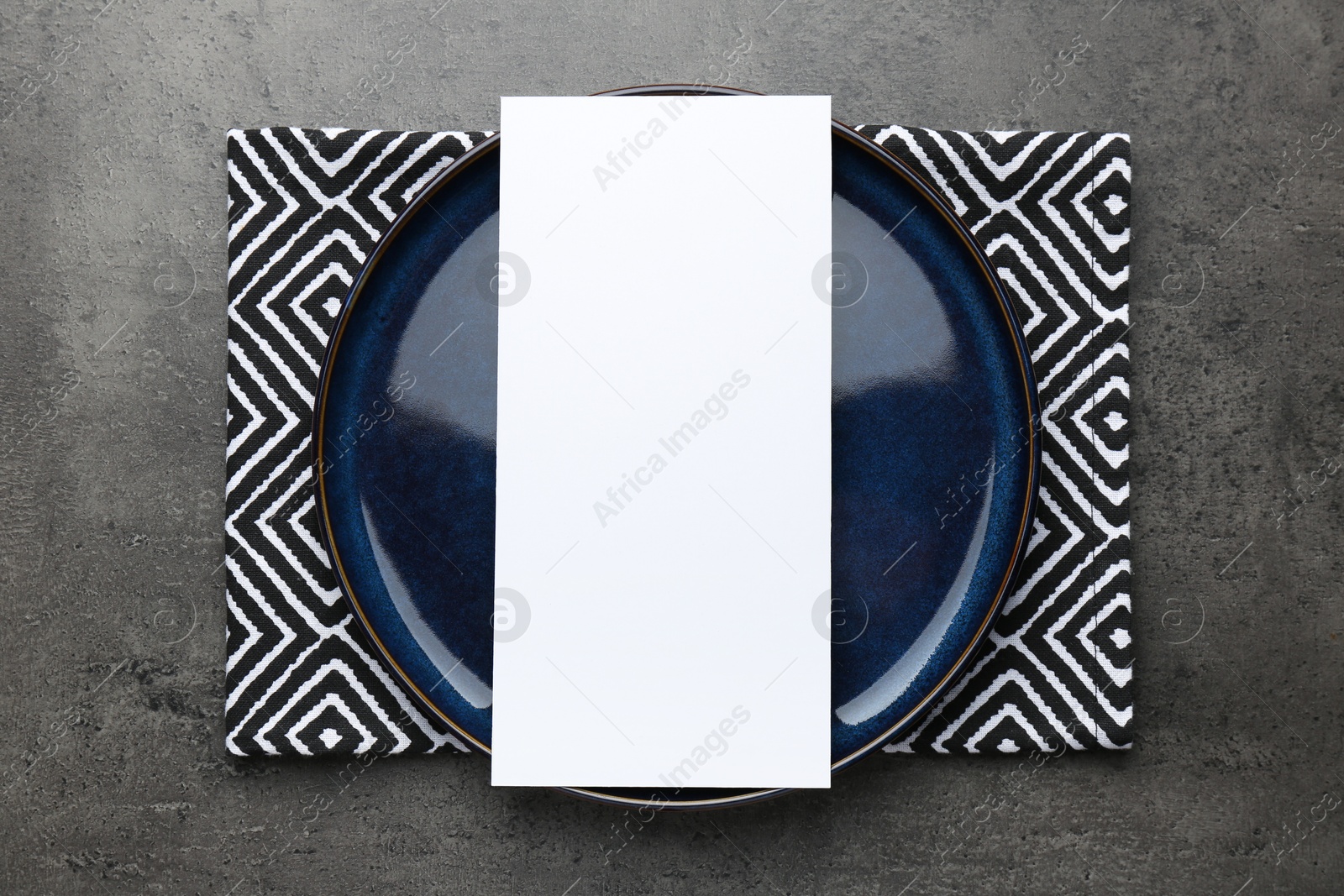 Photo of Empty menu, plate and napkin on grey table, top view. Mockup for design