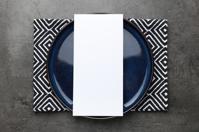 Photo of Empty menu, plate and napkin on grey table, top view. Mockup for design