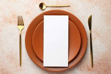 Photo of Empty menu, cutlery and plates on color textured table, top view. Mockup for design