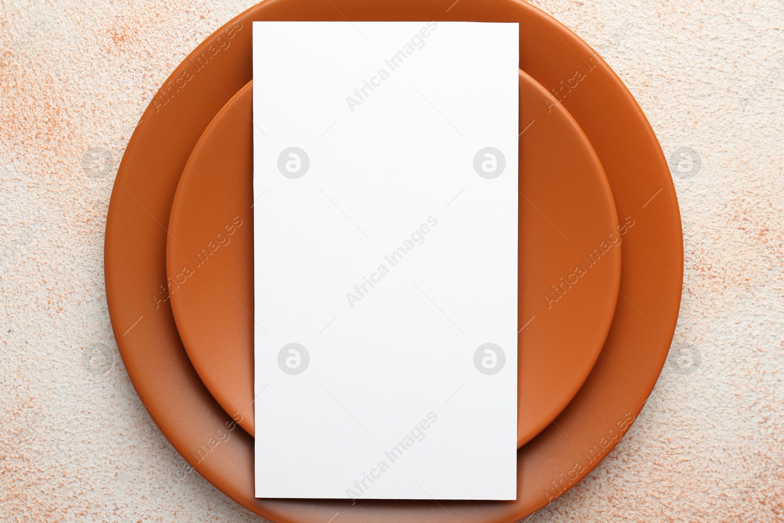 Photo of Empty menu and plates on color textured table, top view. Mockup for design