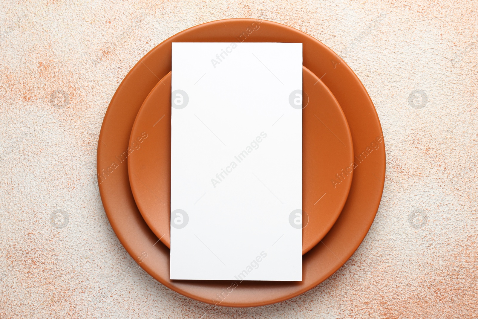 Photo of Empty menu and plates on color textured table, top view. Mockup for design