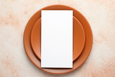 Photo of Empty menu and plates on color textured table, top view. Mockup for design