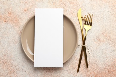 Empty menu, cutlery and plate on color textured table, top view. Mockup for design