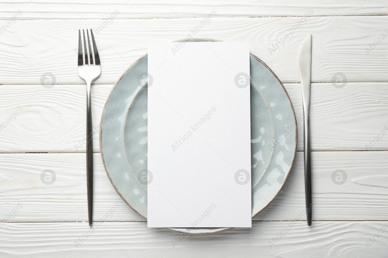 Photo of Empty menu, cutlery and plate on white wooden table, top view. Mockup for design