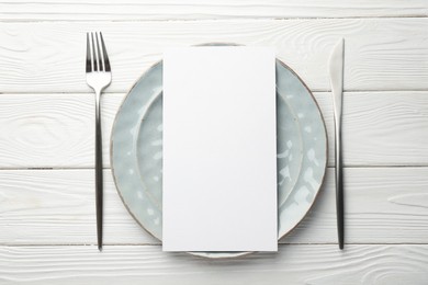 Photo of Empty menu, cutlery and plate on white wooden table, top view. Mockup for design