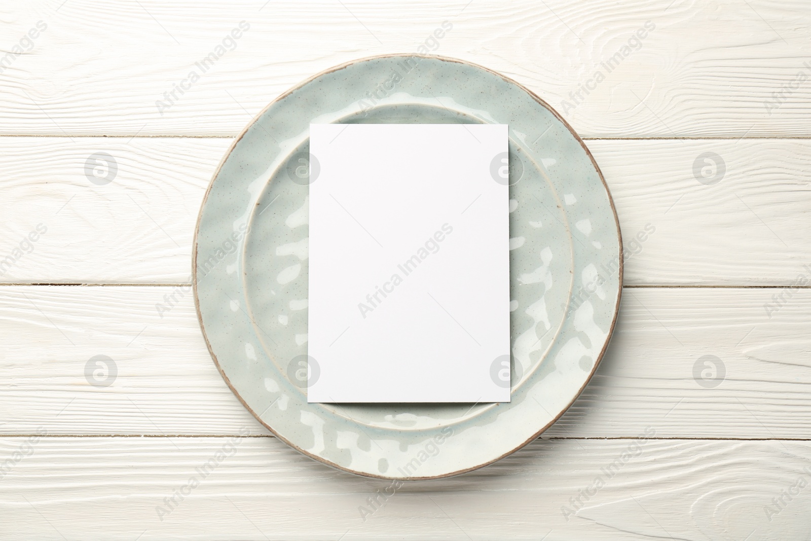 Photo of Empty menu and plate on white wooden table, top view. Mockup for design