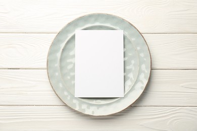 Photo of Empty menu and plate on white wooden table, top view. Mockup for design