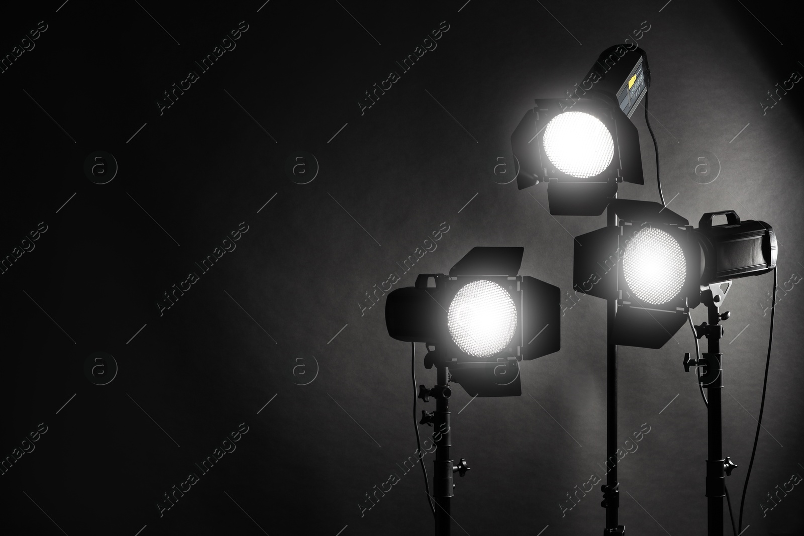 Photo of Dark photo background and professional lighting equipment in studio. Space for text