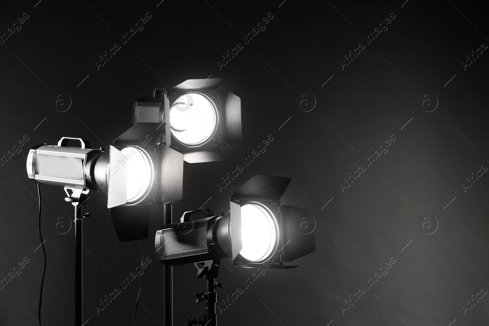 Photo of Dark photo background and professional lighting equipment in studio. Space for text