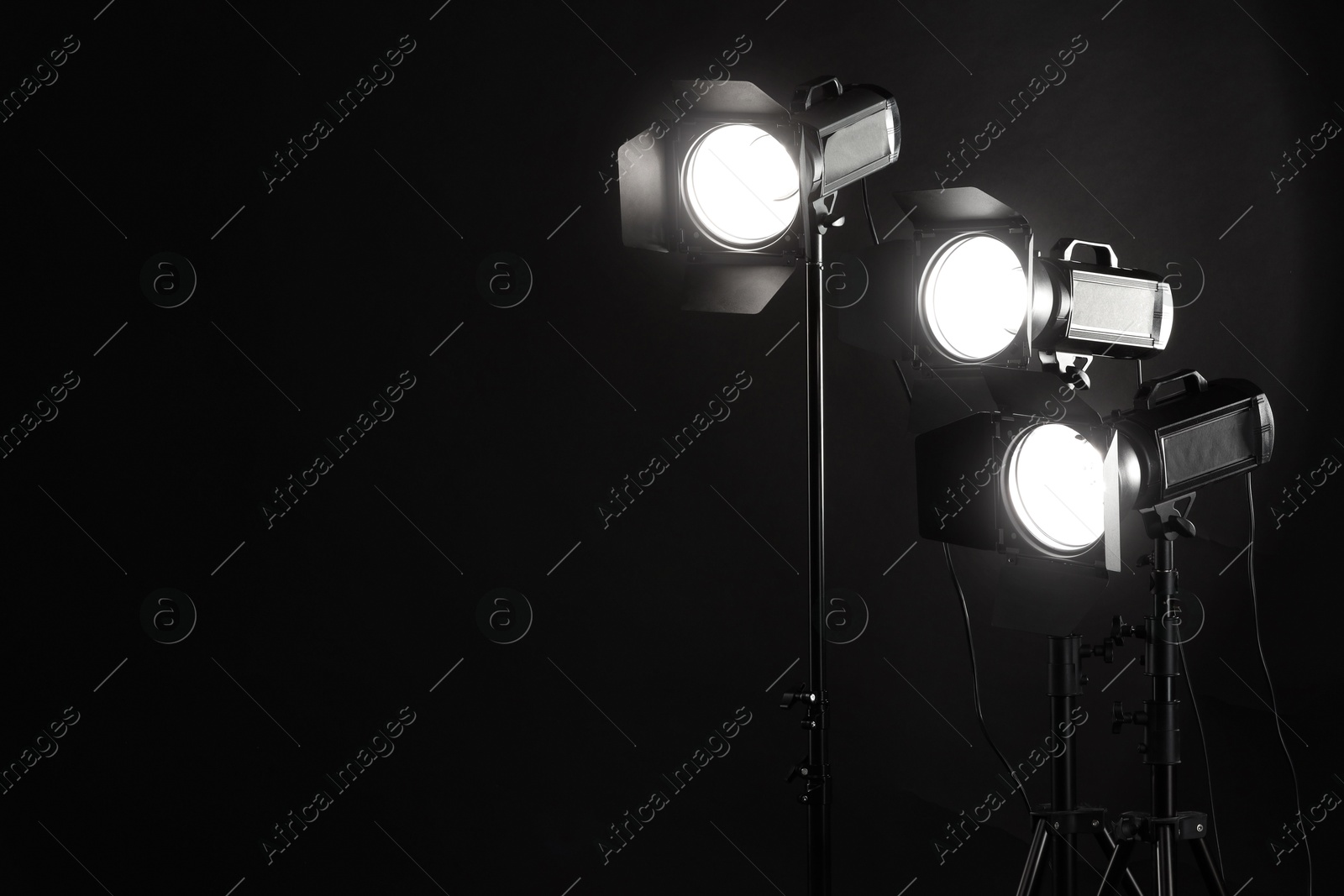 Photo of Dark photo background and professional lighting equipment in studio. Space for text