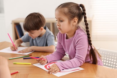 Cute little children drawing at wooden table indoors