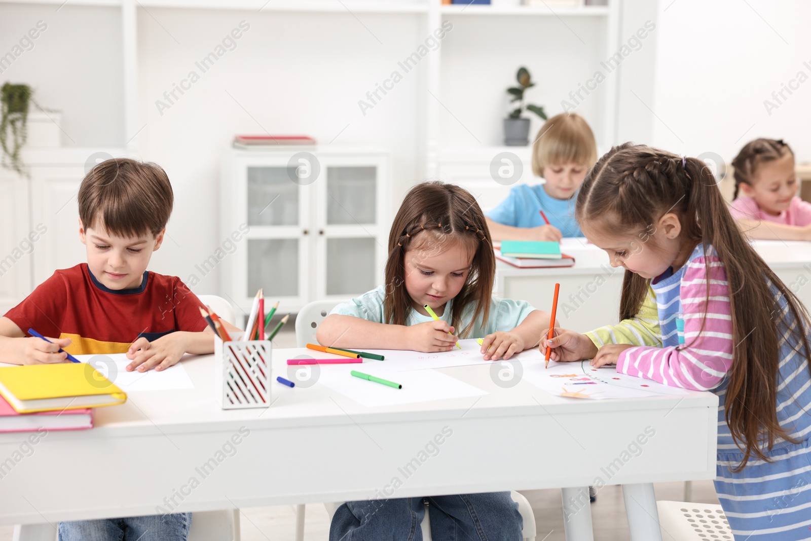 Photo of Group of children drawing at table indoors