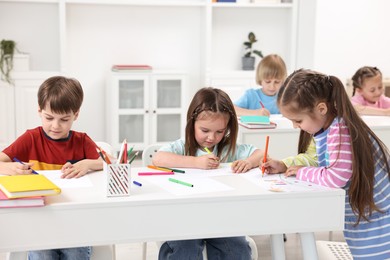 Photo of Group of children drawing at table indoors