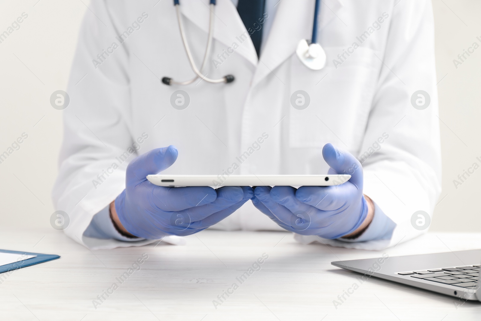 Photo of Doctor with tablet at white wooden table, closeup
