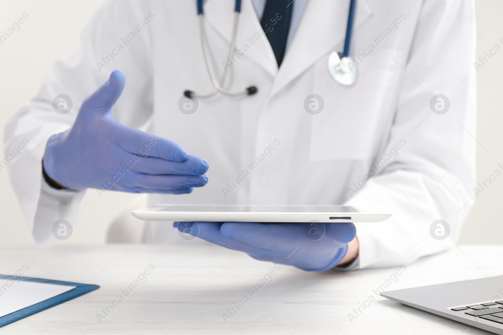 Photo of Doctor with tablet at white wooden table, selective focus