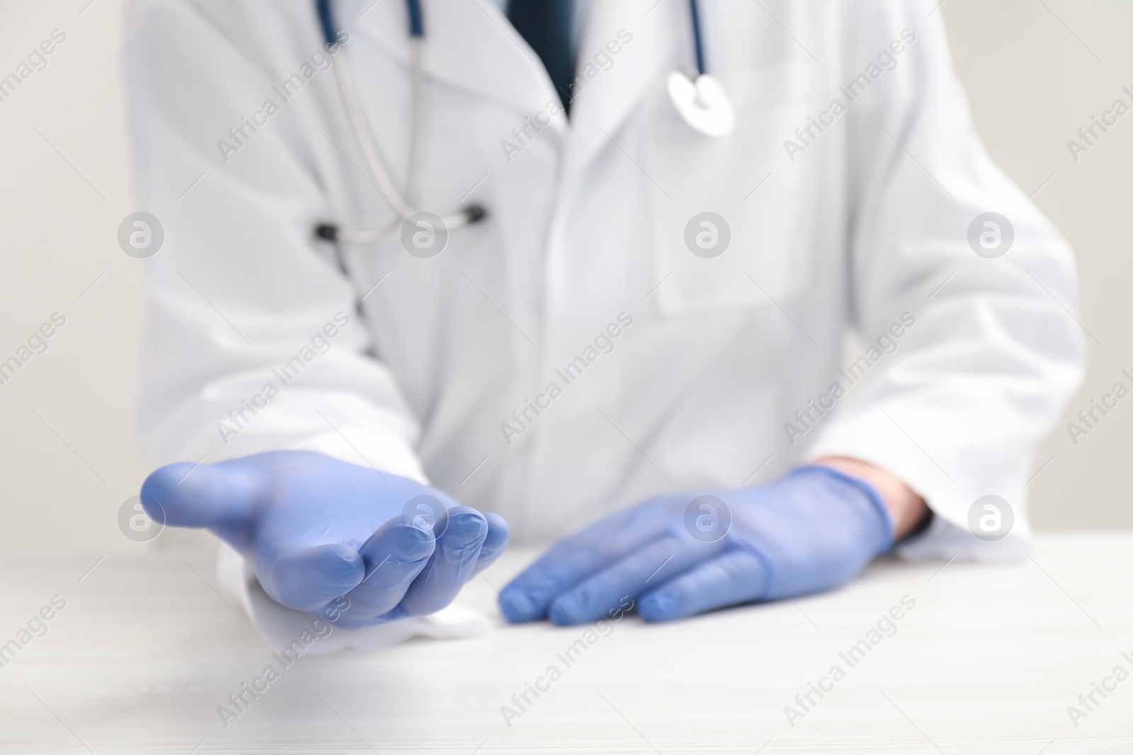 Photo of Doctor in gloves holding something at white table, selective focus